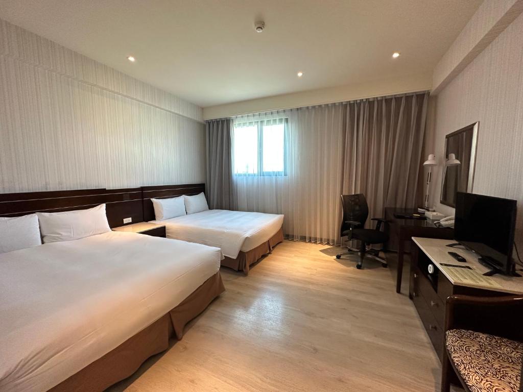 a hotel room with two beds and a desk at Young Soarlan Hotel - Tainan in Tainan