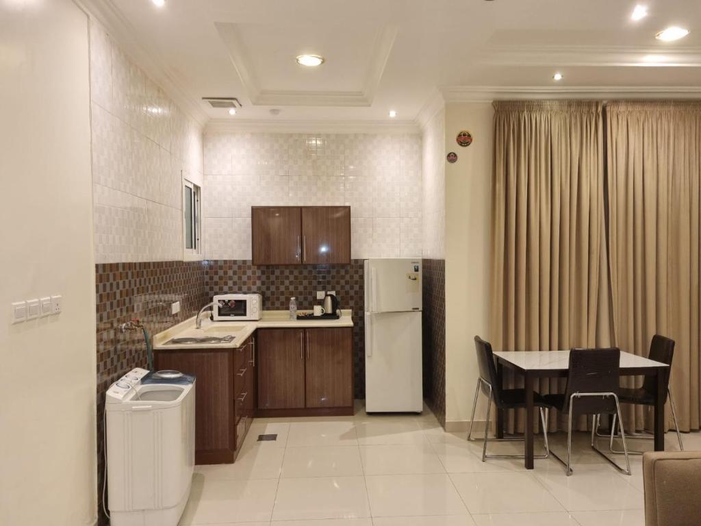 a kitchen with a table and a white refrigerator at تاج الحمراء للاجنحة الفندقية Taj Al Hamra Hotel Suites in Riyadh