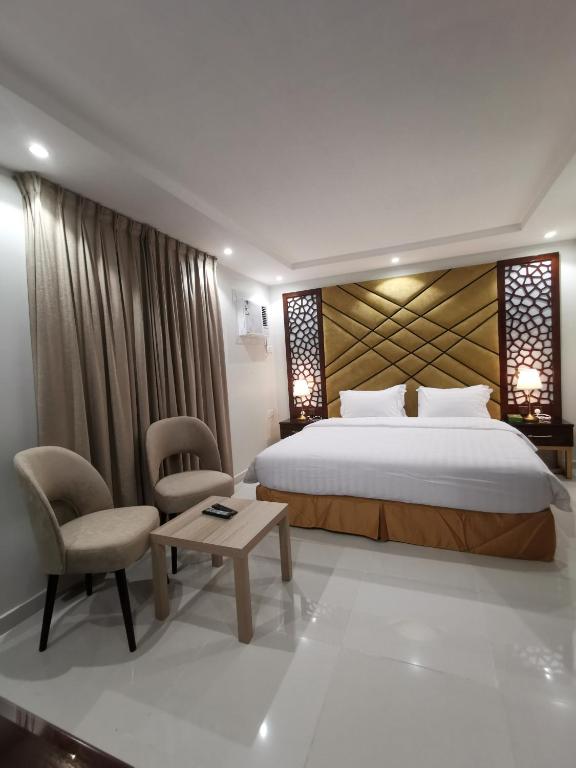 a bedroom with a bed and a chair and a table at شقق جيهان الخاصة in Al Madinah