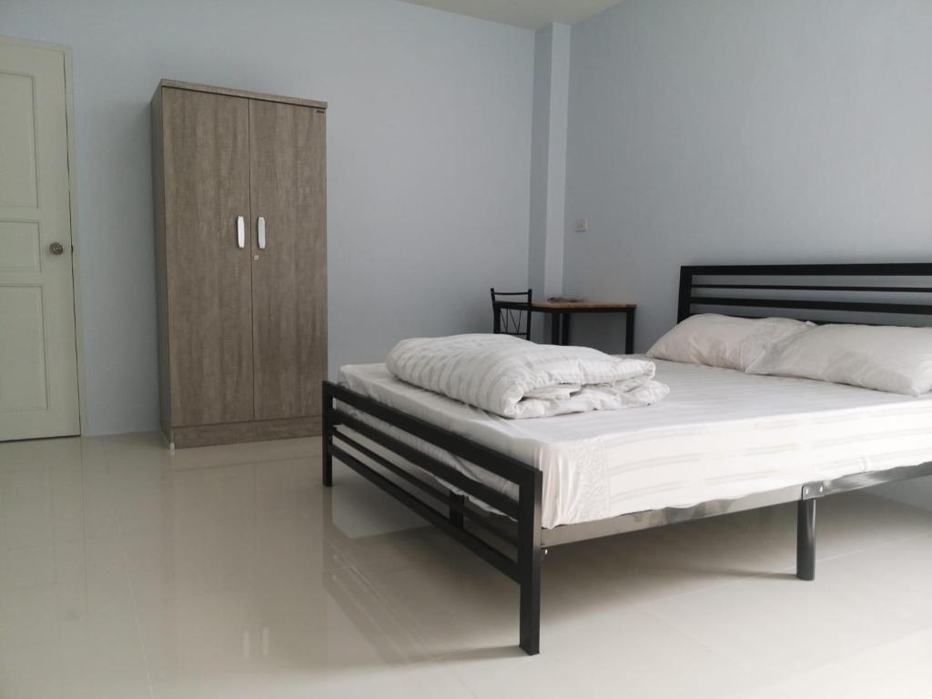 a bedroom with a bed with white sheets and a wooden cabinet at Homie in Ban Tha Kham