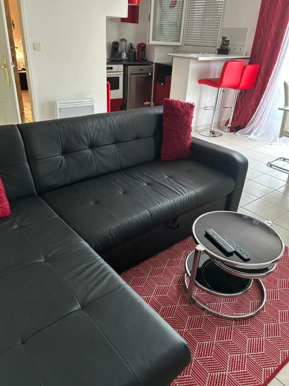 - un canapé noir dans le salon avec une table dans l'établissement APPT MONTPELLIER 2 CHAMBRES et 10 minutes des Plages, à Montpellier