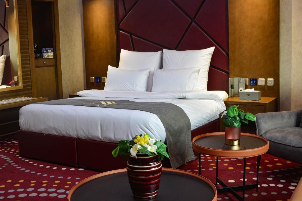Redwaves Hotel في جدة: غرفه فندقيه بسرير وكرسي وطاولات