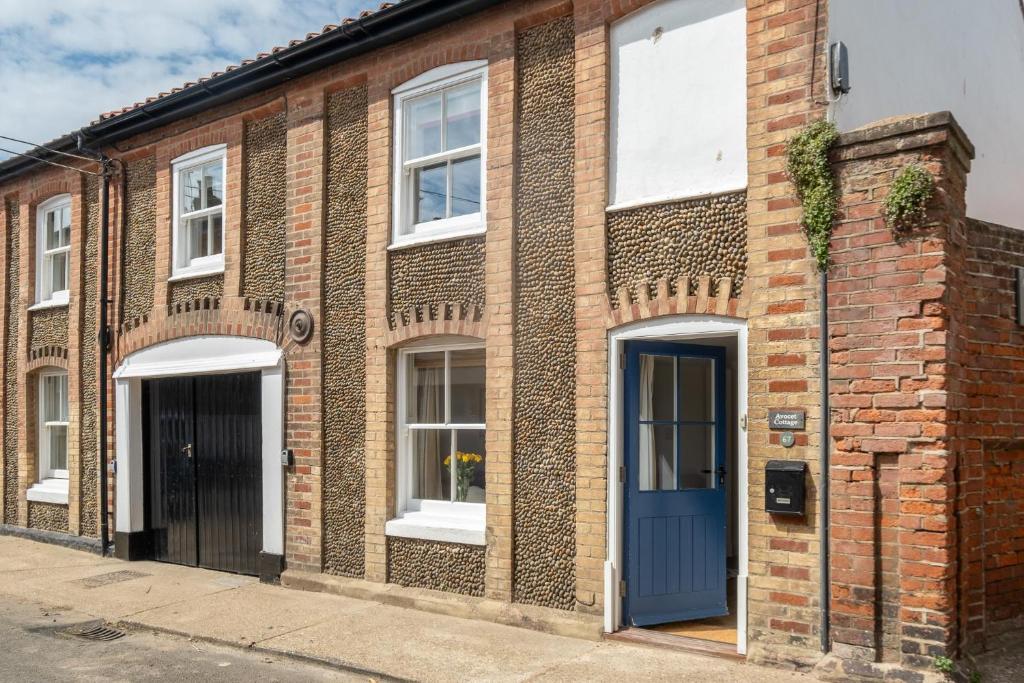 ein Backsteingebäude mit blauer Tür auf einer Straße in der Unterkunft Avocet Cottage in Aldeburgh