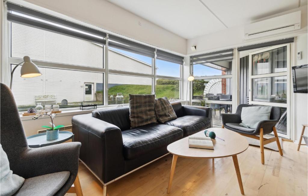 una sala de estar con un sofá de cuero negro y sillas en Fan Bad, Lejl, 19 en Fanø