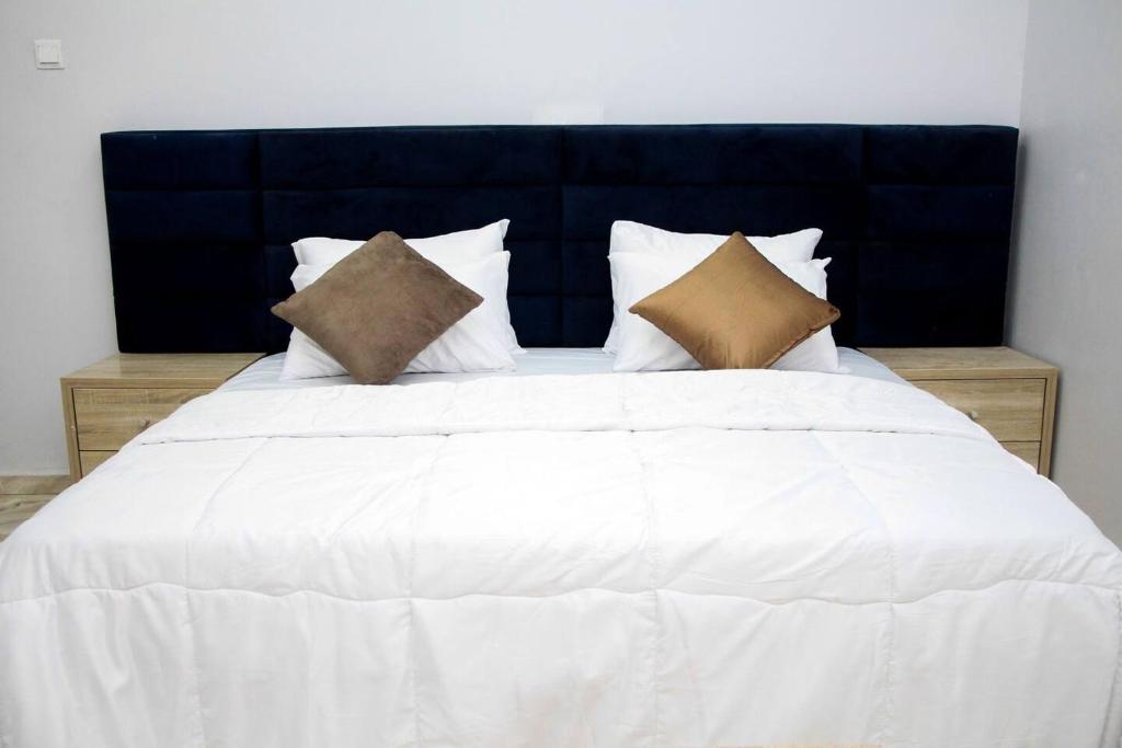 een groot wit bed met 2 kussens erop bij CIS Apartments in Abuja