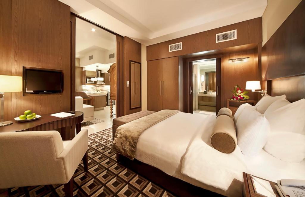 a hotel room with a large bed and a living room at Oaks Liwa Executive Suites in Abu Dhabi