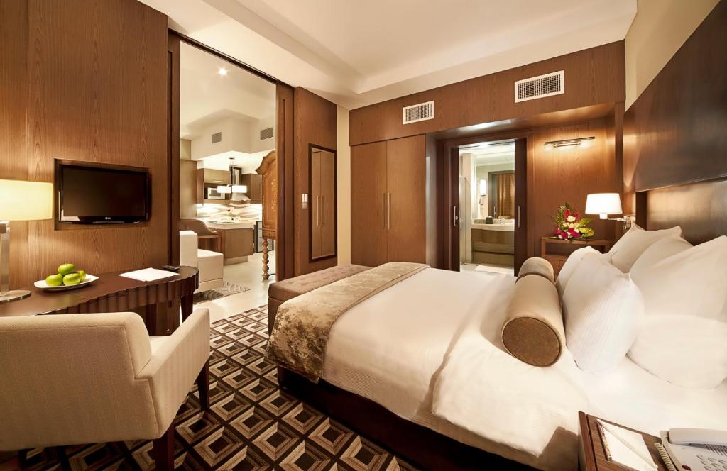 a hotel room with a large bed and a living room at Oaks Liwa Executive Suites in Abu Dhabi