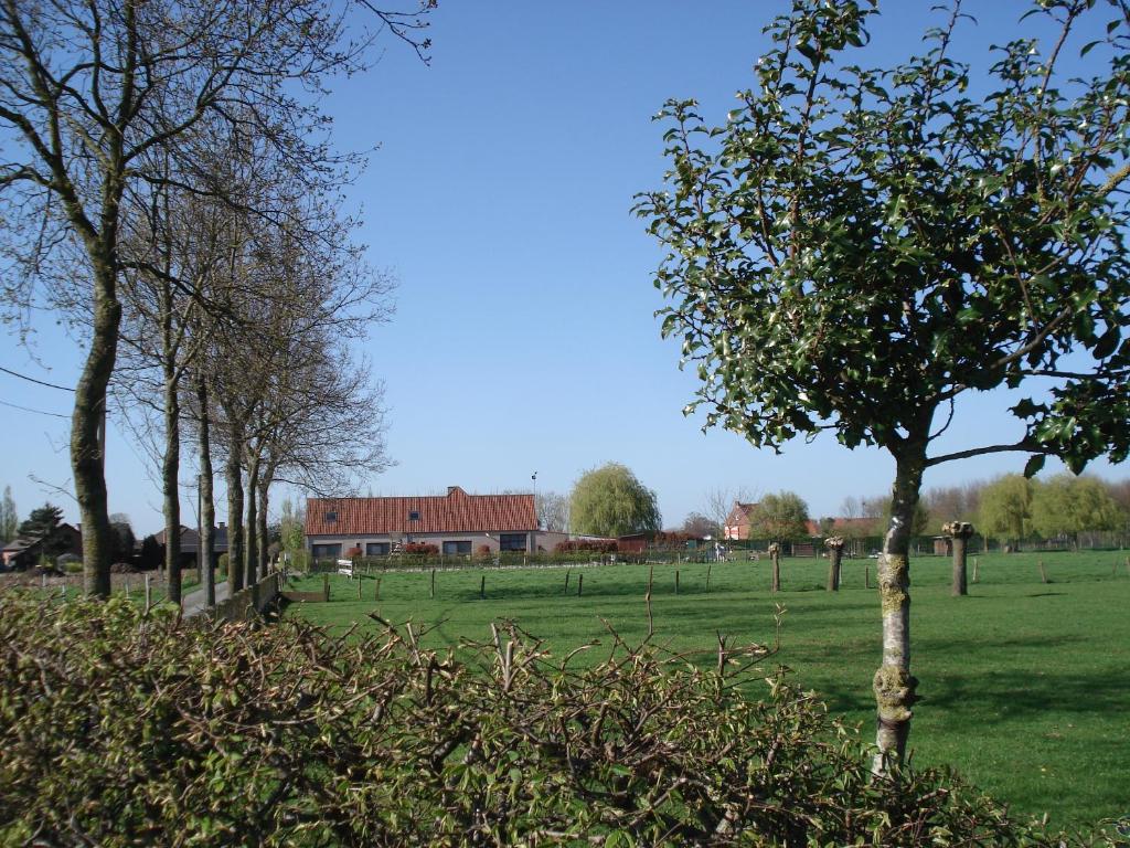 a field with trees and a building in the background at Apollonia in Aalter