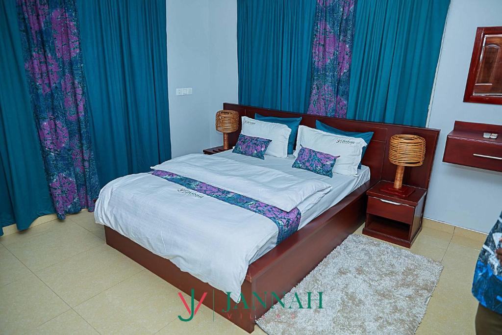 1 dormitorio con 1 cama con cortinas azules en JANNAH VILLAS - GHANA, en Adentan