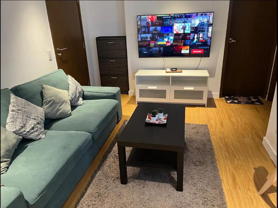 a living room with a blue couch and a tv at Modern and Comfortable Staycation - Unit 3718 Novotel Tower in Manila