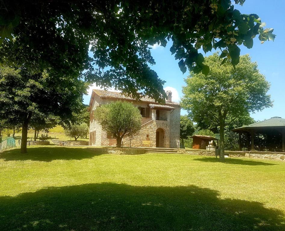 una gran casa de piedra en un campo con árboles en Agriturismo Villa Sant' Andrea, en Gubbio