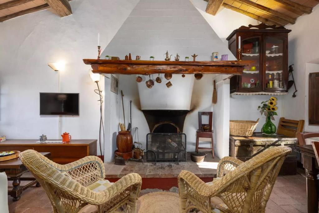 ein Wohnzimmer mit einem Kamin und einigen Stühlen in der Unterkunft CASA IL MANDORLO NEL CHIANTI in Castellina in Chianti
