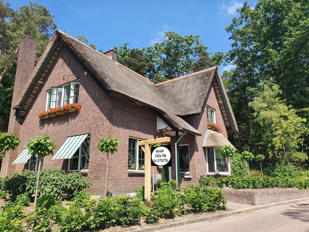 uma casa de tijolos com uma placa em frente em Huize Villa Vos em Hellendoorn