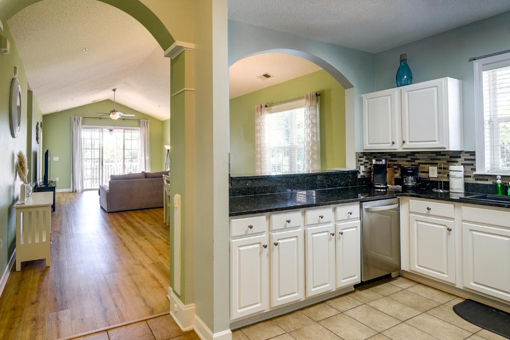 a kitchen with white cabinets and a living room at Barefoot Resort Condo with Pools and Balcony! in Myrtle Beach