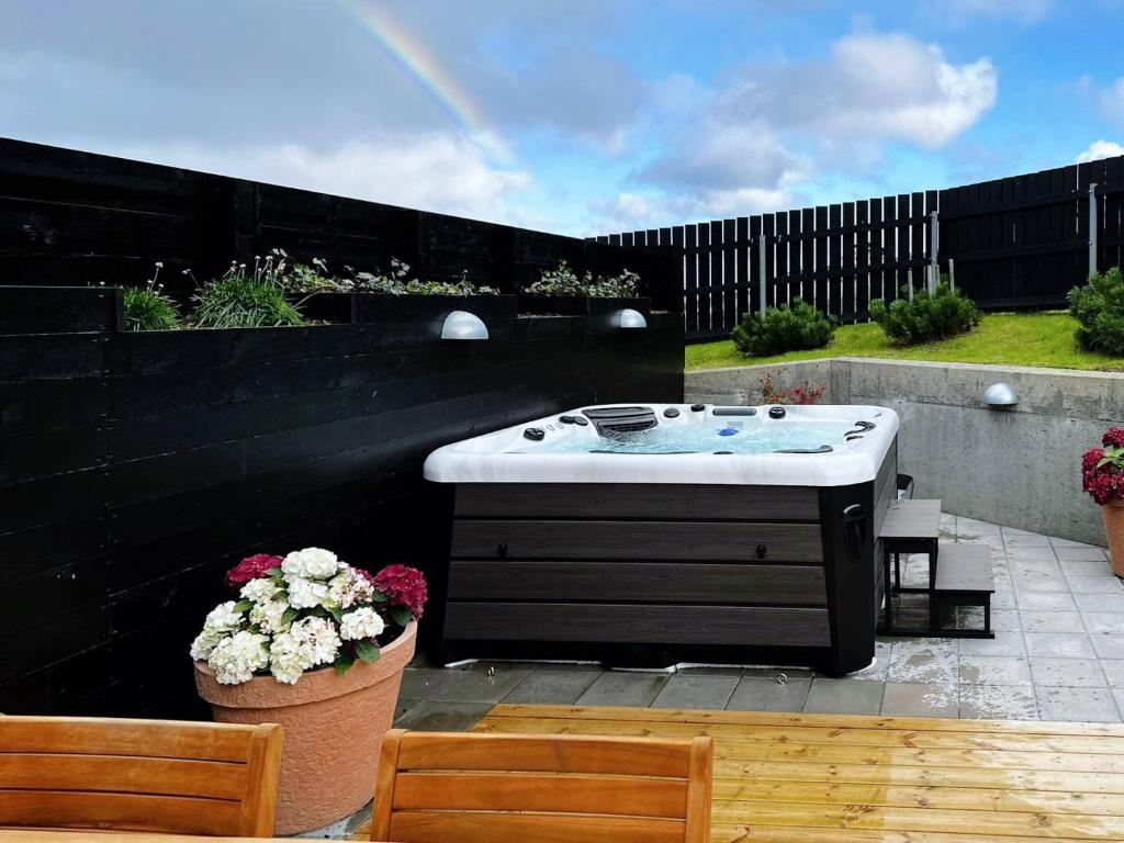 uma banheira de hidromassagem num pátio com 2 cadeiras e flores em Stunning Ocean View Penthouse Apartment em Øravík