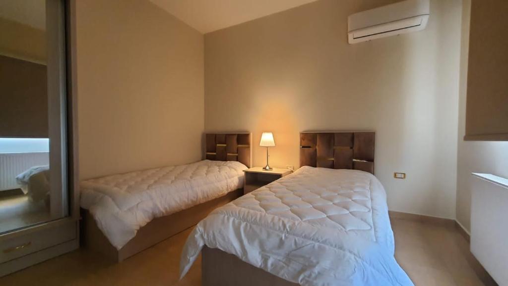 een slaapkamer met 2 bedden en een spiegel bij CMK Housing in Madaba