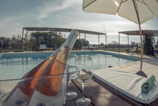 Una botella de vino sentada en una mesa junto a una piscina en Finca del Sacramento, en Colonia del Sacramento