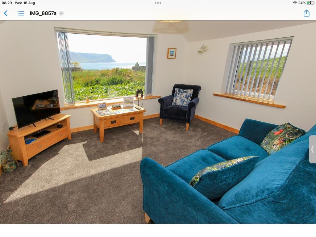 a living room with a blue couch and a television at Reka Vik in Stromness