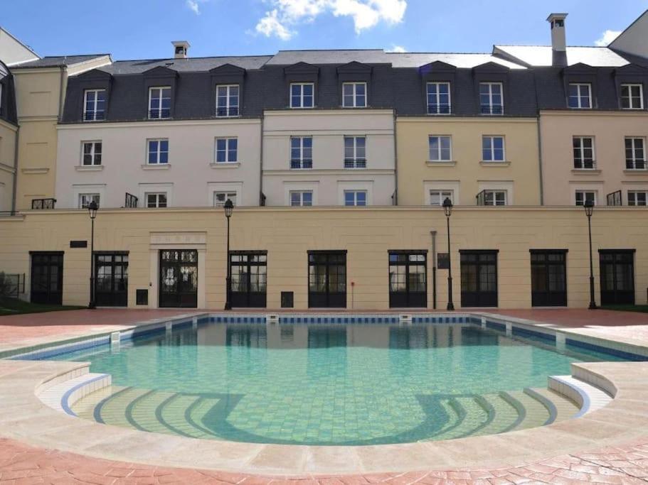 a large building with a large pool in front of it at Disneyland Deluxe flat, outside pool, Climatisation, 1 min to Disney Parks in Serris