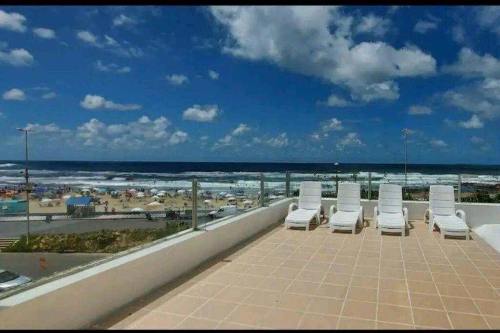 a row of white lounge chairs on a balcony overlooking the beach at Edificio Punta del Este in Punta del Este