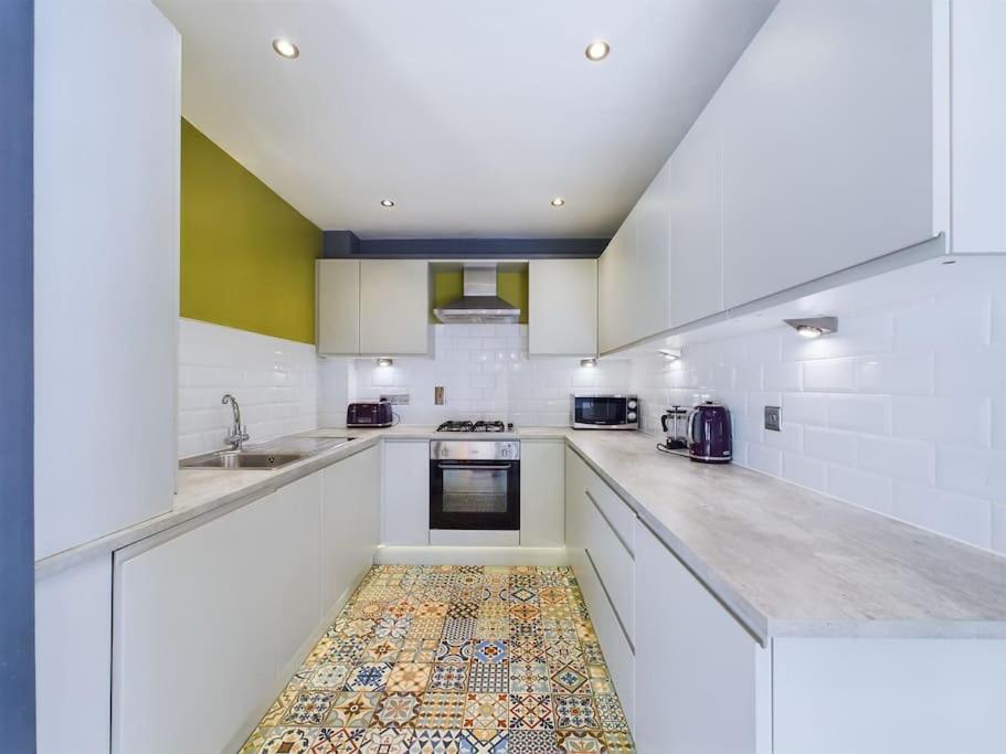 a kitchen with white cabinets and a tile floor at Donegall Sq Apt at City Gate, Belfast City Centre in Belfast