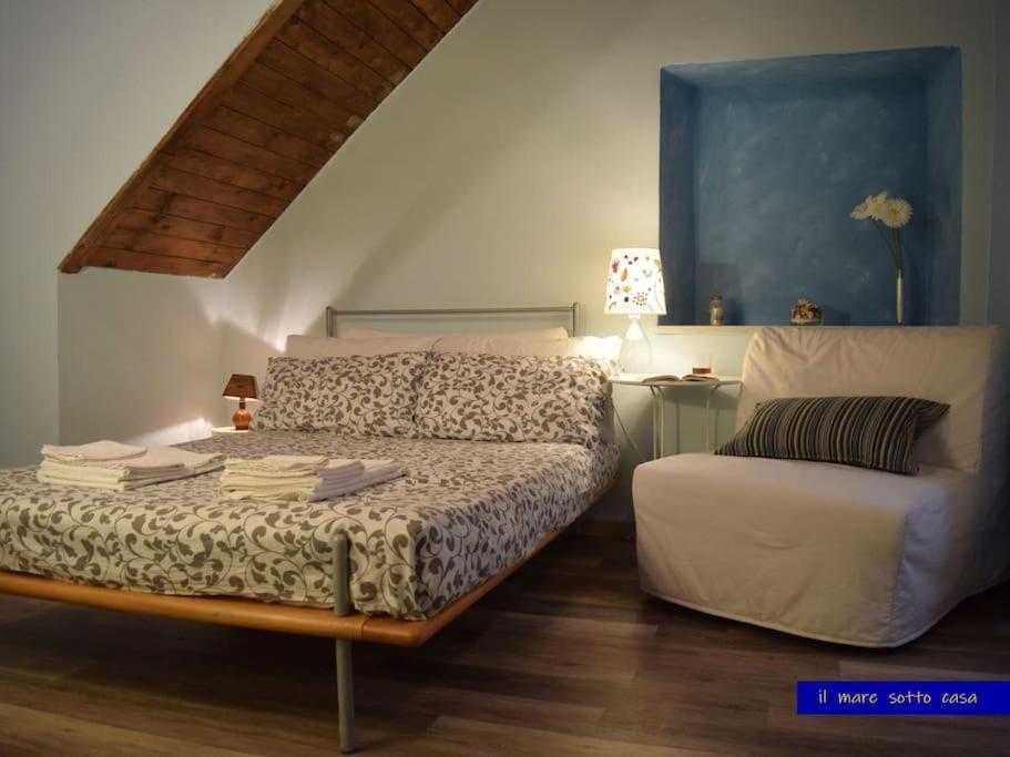 ein Schlafzimmer mit einem Bett und einem Stuhl darin in der Unterkunft IL MARE SOTTO CASA - Free parking in Fezzano