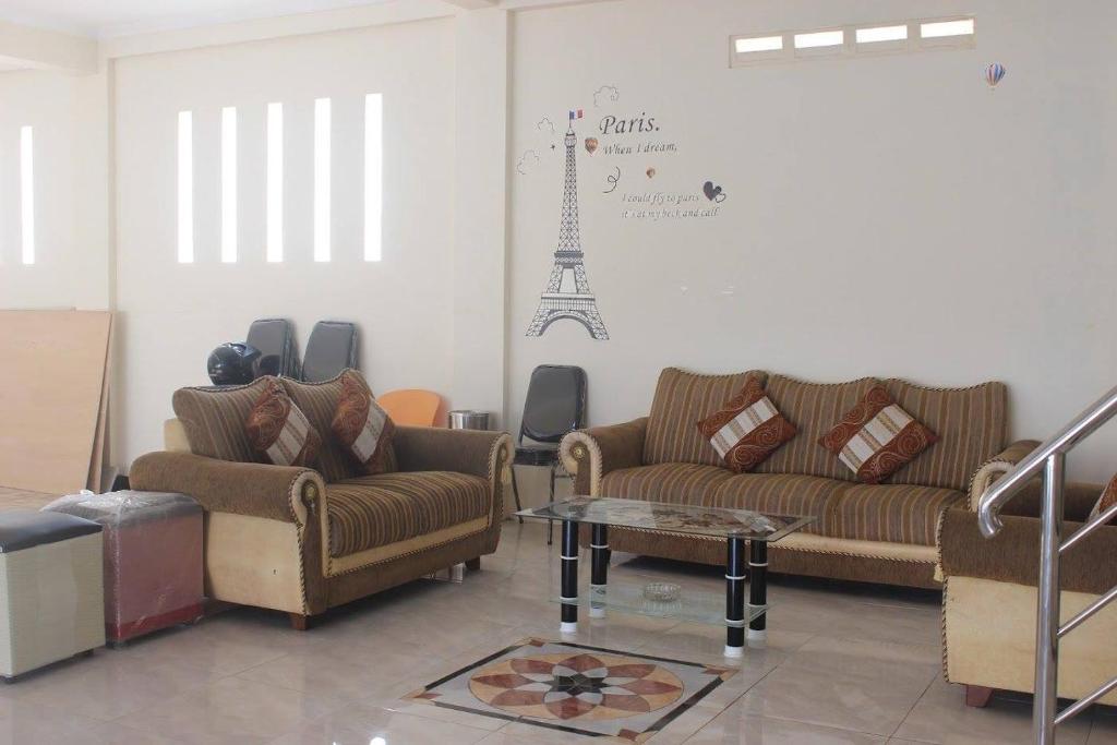 a living room with couches and a table and the eiffel tower at Solo Nadamax City Guest House Syariah in Bonorejo
