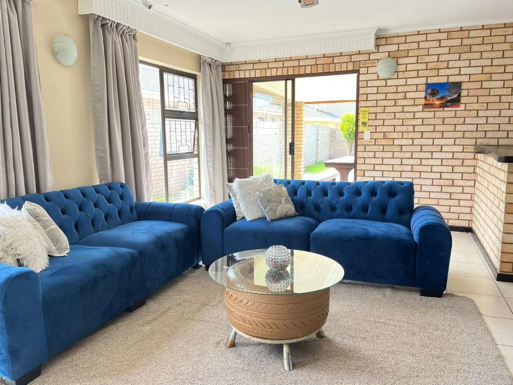 a living room with blue couches and a glass table at Summerstrand holiday home in Summerstrand