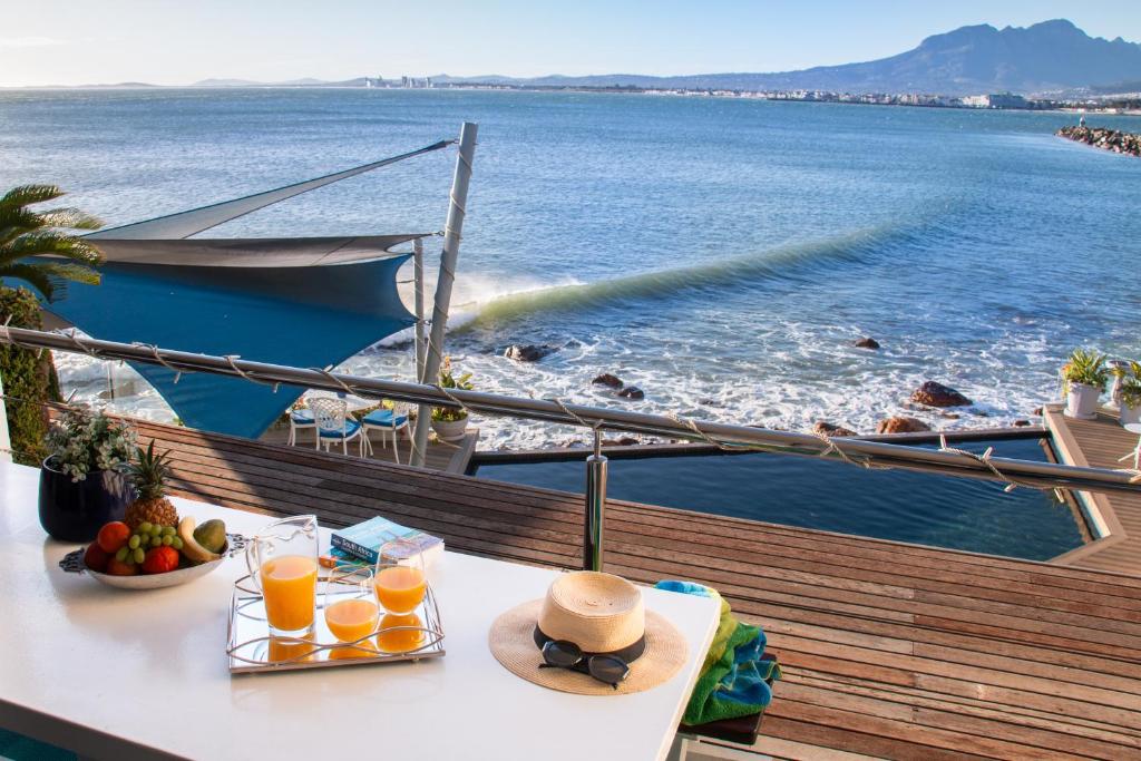 uma mesa com copos de sumo de laranja e um barco em 185 on BEACH Boutique Suites em Gordonʼs Bay