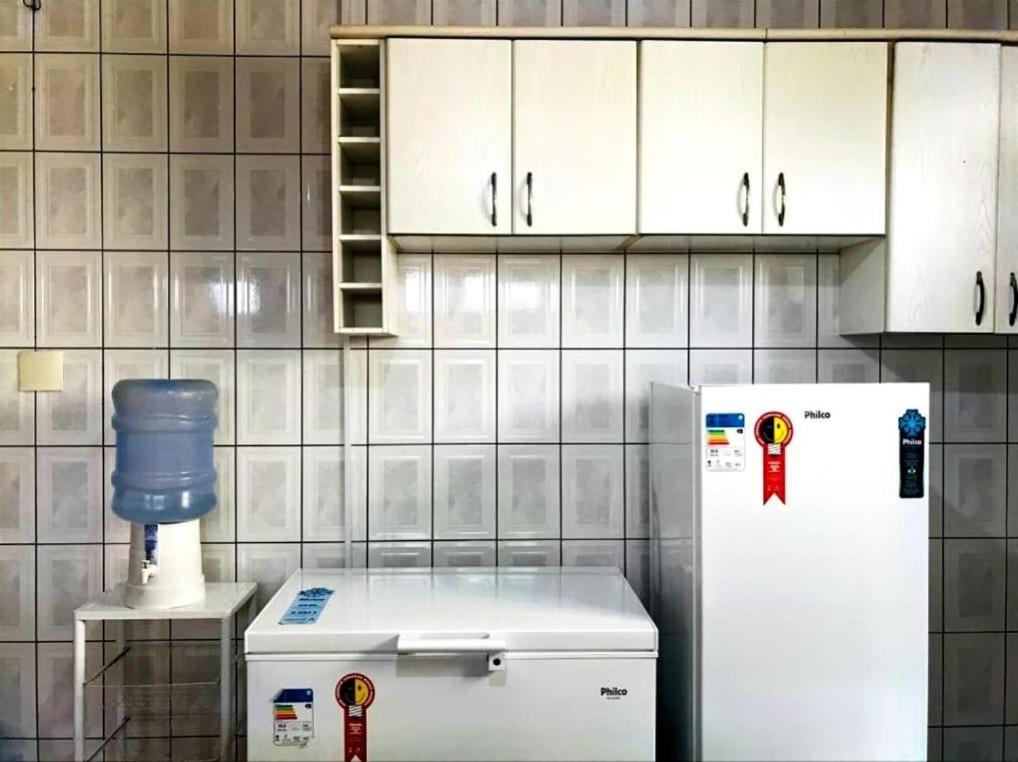 uma cozinha com frigorífico e armários brancos em Duque Hostel em Belém