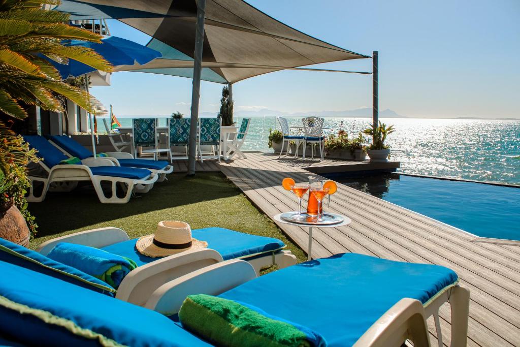 a wooden deck with chairs and a swimming pool at 185 on BEACH Boutique Suites in Gordonʼs Bay