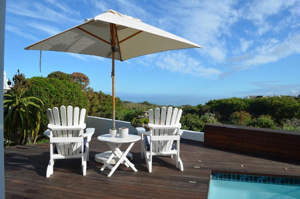 dwa krzesła i stół z parasolem na tarasie w obiekcie Stunning Beach House in Grotto Bay w mieście Grotto Bay