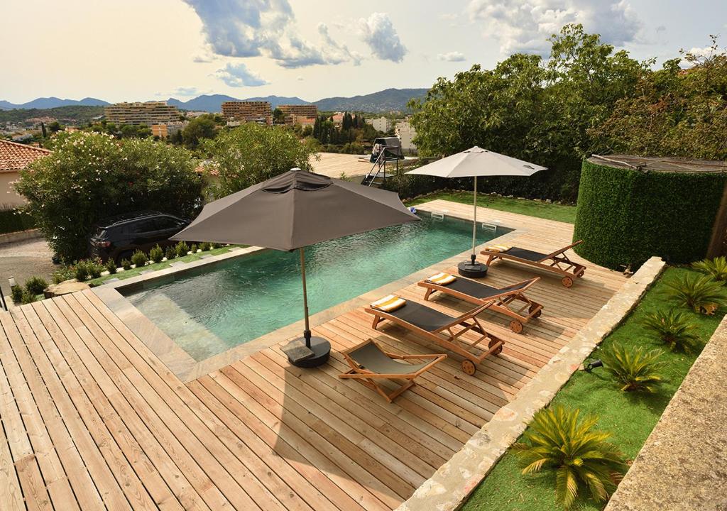 a swimming pool with two chairs and an umbrella at La Villa d’Emma in Mougins