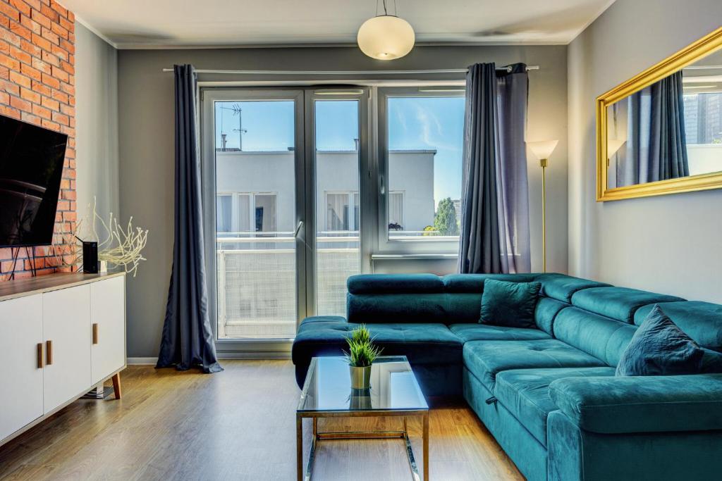 sala de estar con sofá azul y ventana en Allure Nautica Aparthotel en Szczecin