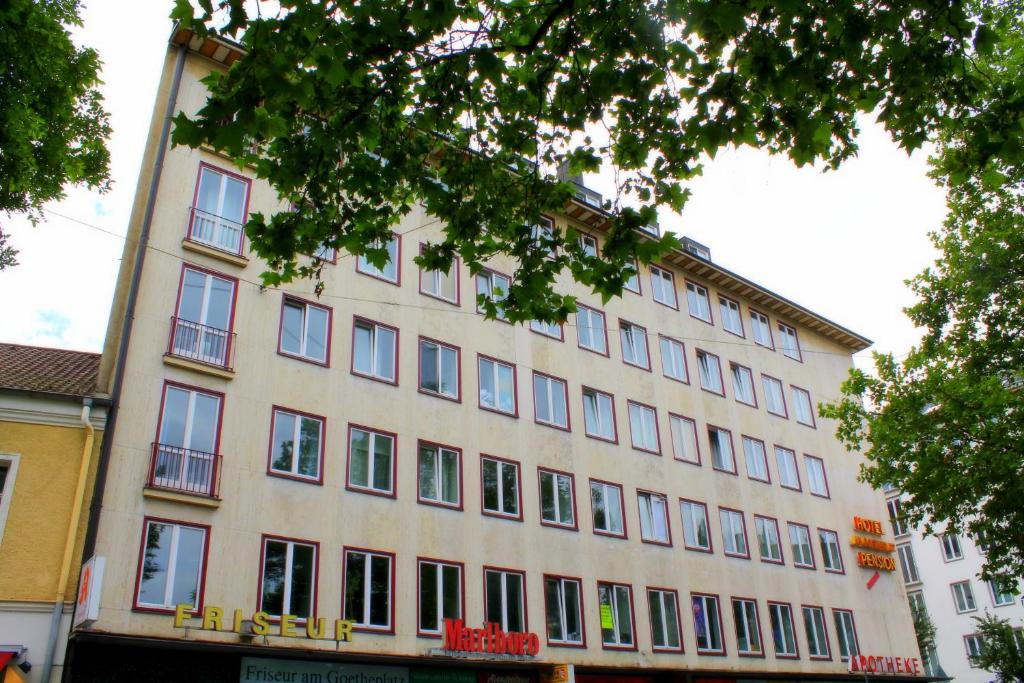 un grand bâtiment avec de nombreuses fenêtres donnant sur une rue dans l'établissement Hotel Mons am Goetheplatz, à Munich