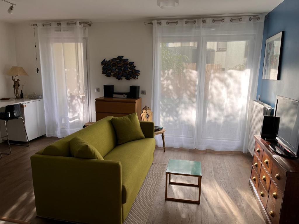 ein Wohnzimmer mit einem grünen Sofa und einem Tisch in der Unterkunft Apartment close to Paris and métro in Le Pré-Saint-Gervais