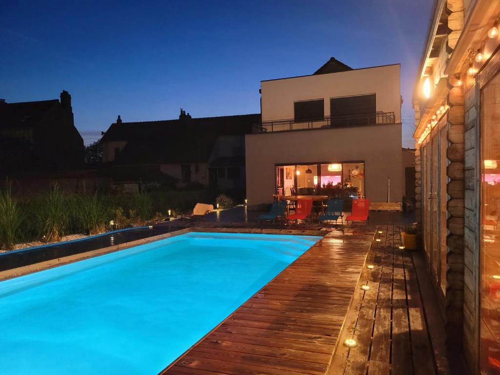 ein Schwimmbad vor einem Haus in der Nacht in der Unterkunft Villa Oriel 1 à NEUFCHATEL-HARDELOT avec piscine privée in Neufchâtel-Hardelot