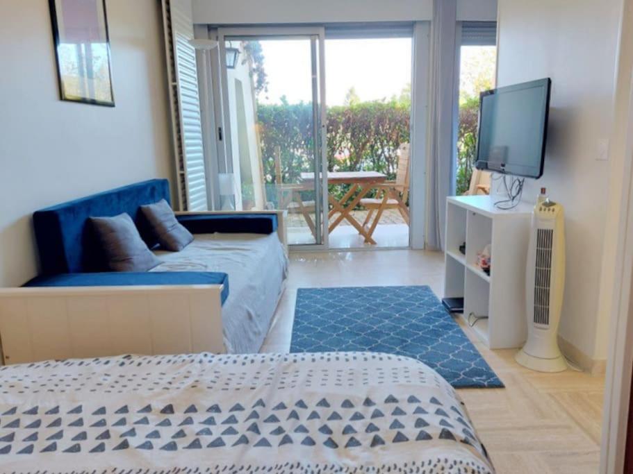 un salon avec un canapé et une télévision dans l'établissement Studio Eleverca 3*- rez de jardin terrasse - Axelle Loc'Appart, à Mandelieu-la-Napoule