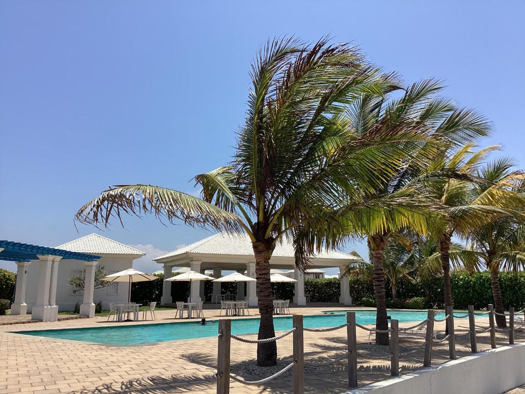 una piscina del complejo con palmeras y sombrillas en CasaMuyuyo - Hermosa Casa de Playa a 1h20 de Guayaquil en Playas
