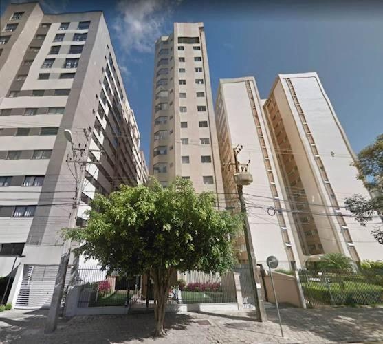 Tre edifici alti con un albero davanti di Flat Jardim Botânico Curitiba até 7 pessoas a Curitiba