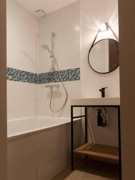 a bathroom with a tub and a sink and a mirror at L’Arabesque, villa de charme avec piscine in Arradon