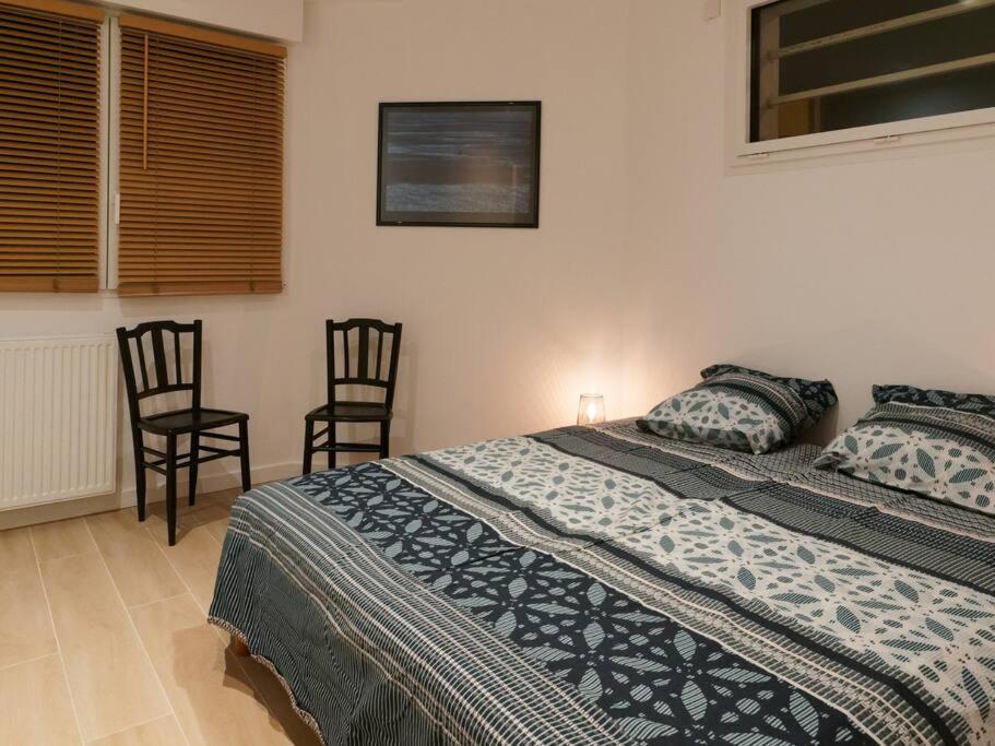 a bedroom with a large bed and two chairs at L’Arabesque, villa de charme avec piscine in Arradon