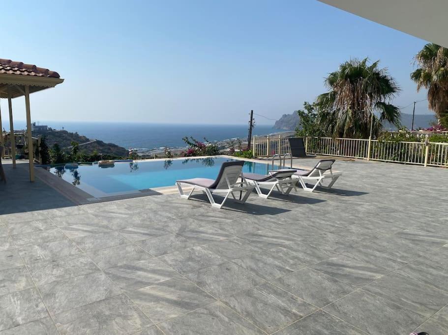 eine Terrasse mit Stühlen und einem Pool in der Unterkunft Villa Venus in Gazipasa