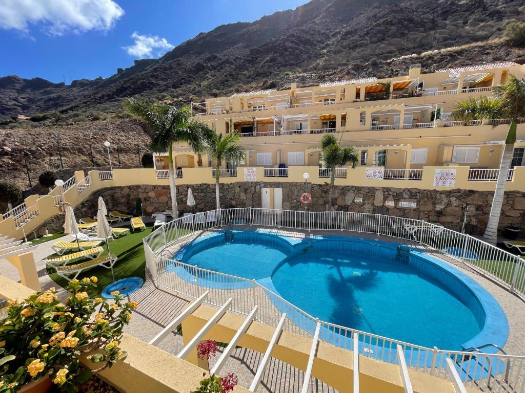 a hotel with a large swimming pool in front of a building at Los Mangueros Beach 6 in Puerto de Mogán