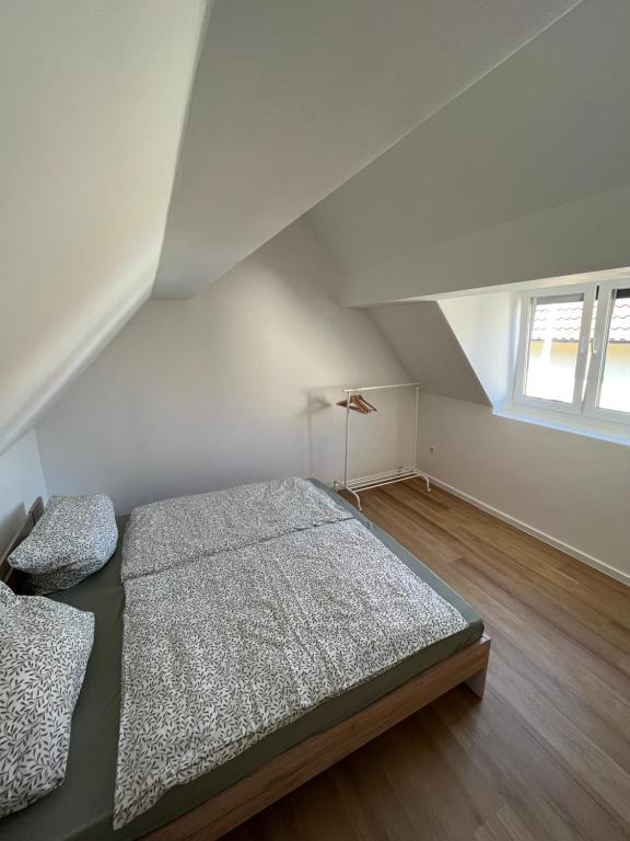 an attic bedroom with a bed and a window at Modernes Haus 5 Min vom See in Waldsee