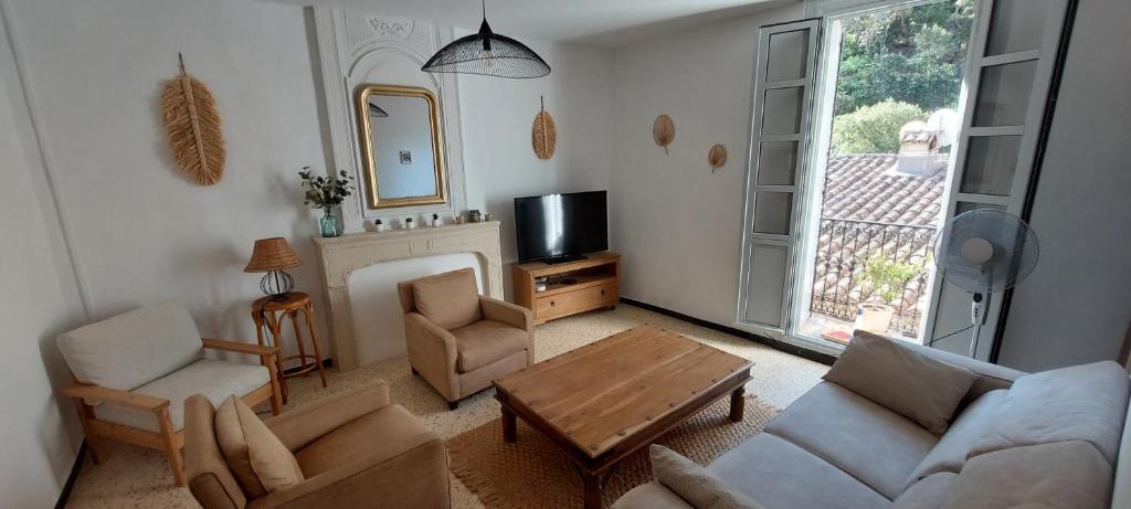un soggiorno con divano, tavolo e TV di La maison de la Traverse a Saint-Guilhem-le-Désert