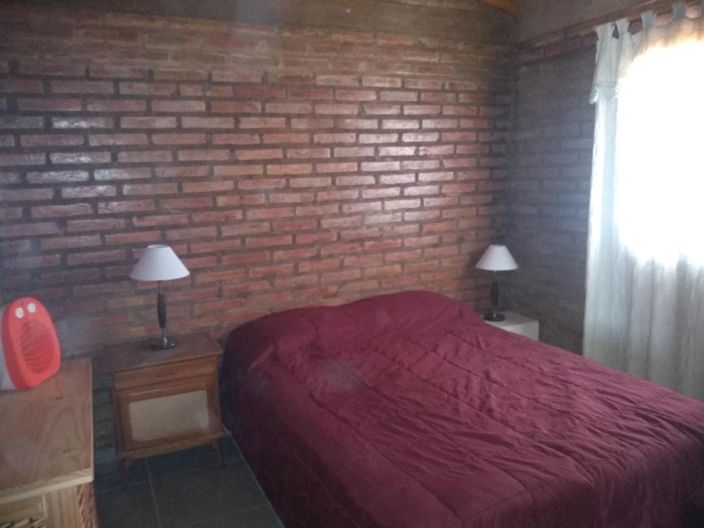 a bedroom with a red bed and a brick wall at La Lechuza in El Volcán