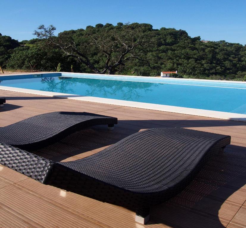 a swimming pool with two chairs in front of it at Casas de Campo do Castro da Cola in Marchicão
