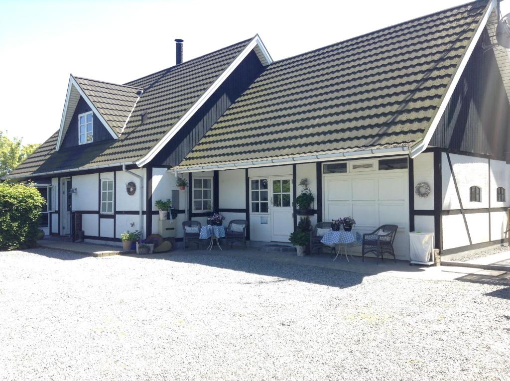 een wit huis met een garage en tafels en stoelen bij Piccobello Bed & Breakfast Valløby Køge in Valløby