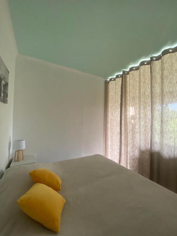 a bedroom with a bed with yellow pillows and a window at Chris&#39;Home2 in Roquebrune-Cap-Martin